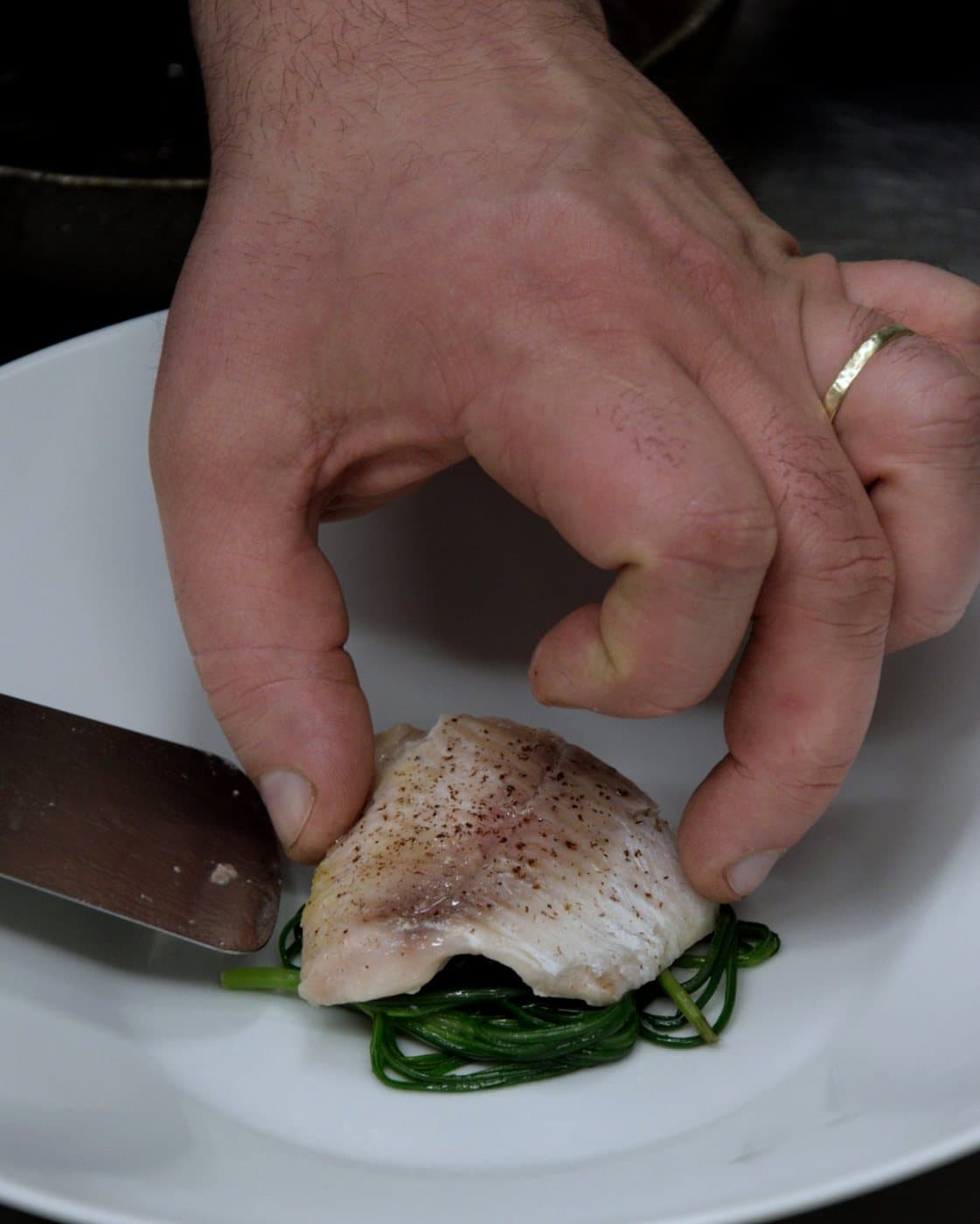 La main du chef dépose un filet de poisson dans l’assiette